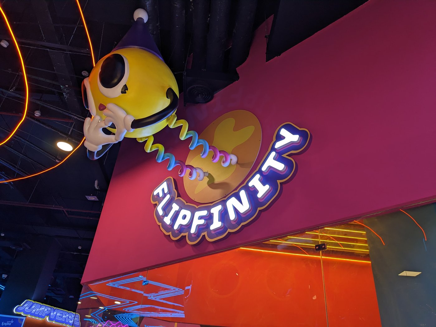 A neon sign reading Flipinity next to a large Boing mascot figure