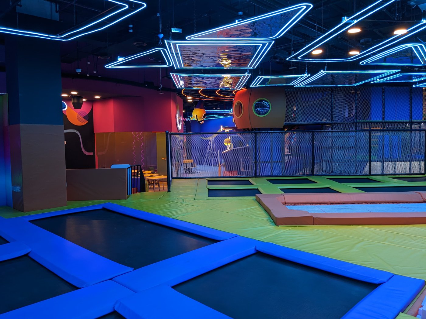 The main trampoline court with colorful court markings and a climbing net overhead