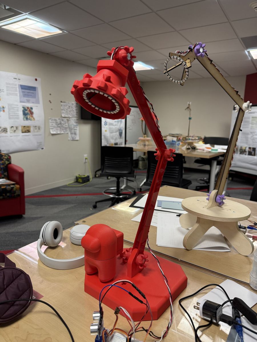 The finished lamp with its red 3D-printed shade and LED ring, sitting on the workshop table