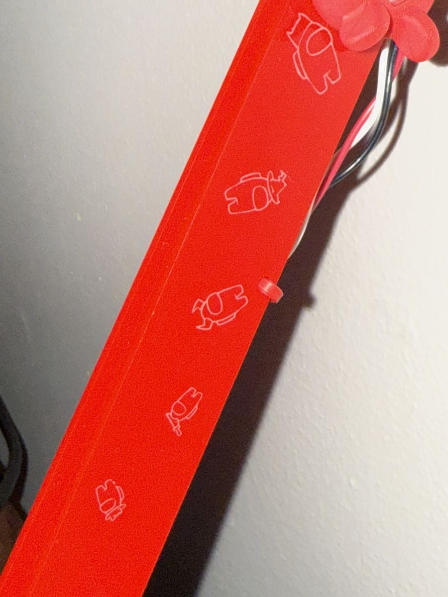 Close-up of the red arm laser-etched with tiny crewmates